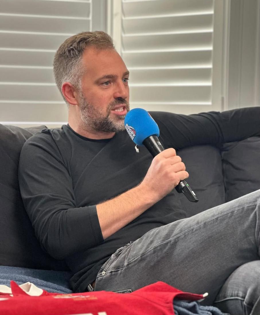 Chris speaking into a 5 Live microphone on a sofa
