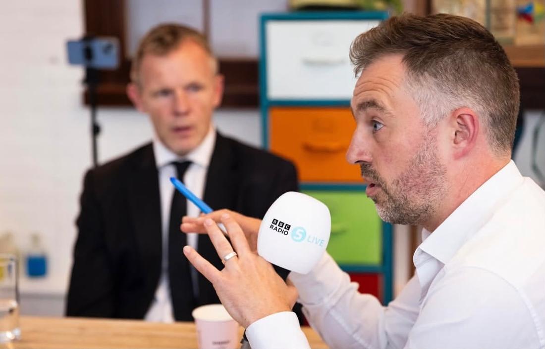 Chris holding a 5 Live microphone in a sit-down interview